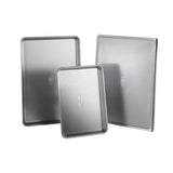 Three metal baking trays with ribbed surface on a white background