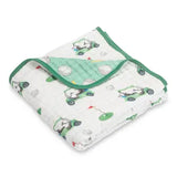 A folded white muslin baby blanket with a green and gray golf cart pattern, featuring a solid green reverse side and trim.