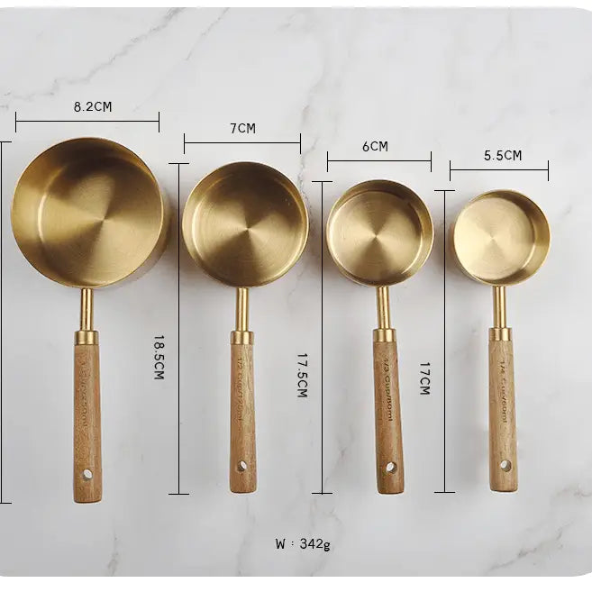 Set of four brass measuring spoons with wooden handles, shown with measurements on a marble background.