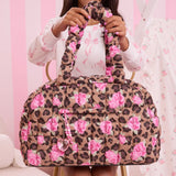 Person holding a leopard print bag with pink flowers against a pink background