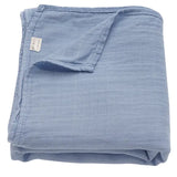 Folded blue fabric blanket with a visible brand label on a white background