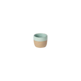 Two-toned ceramic cup with green top and beige bottom on a white background