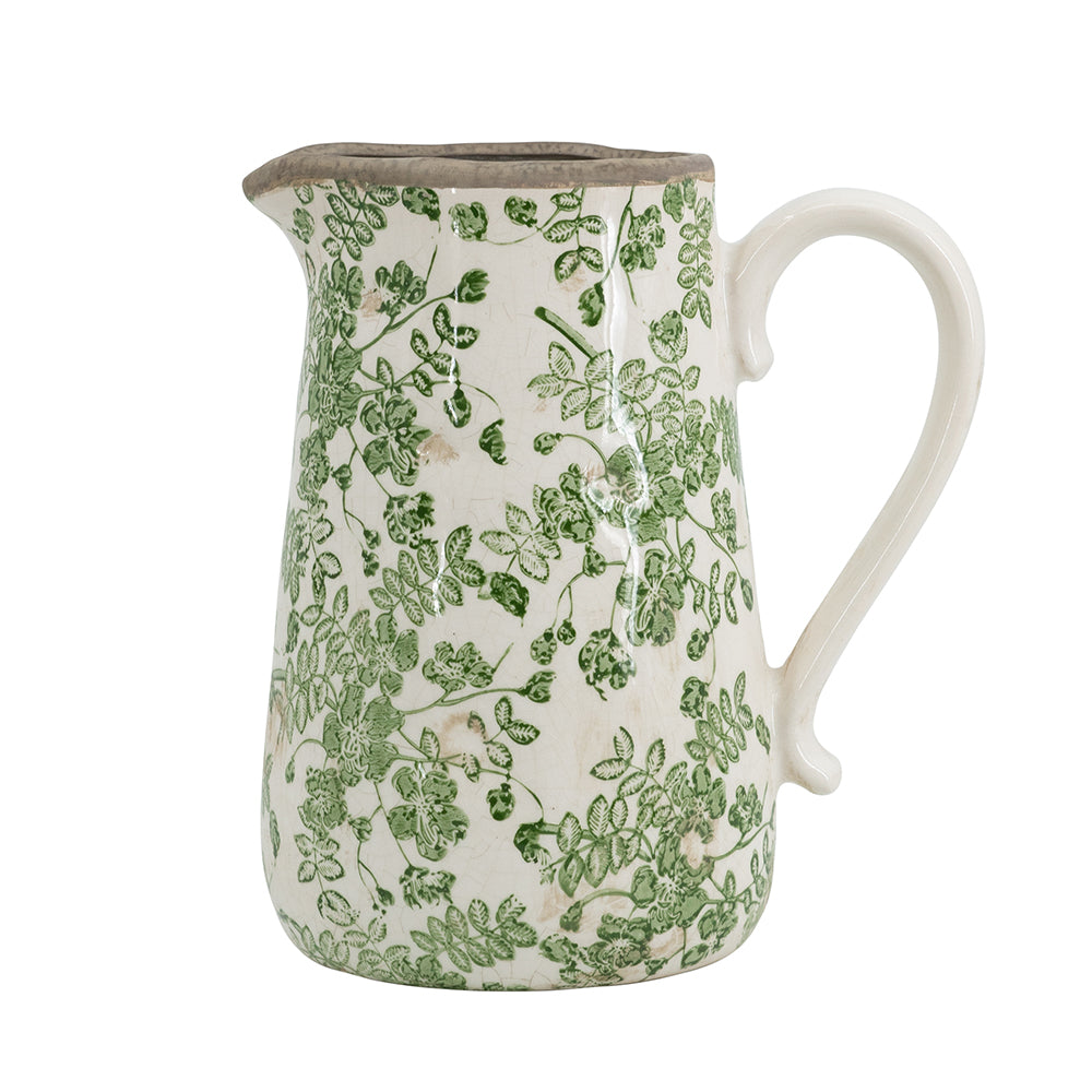 Ceramic pitcher with green floral pattern on a white background