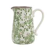 Ceramic pitcher with green floral pattern on a white background