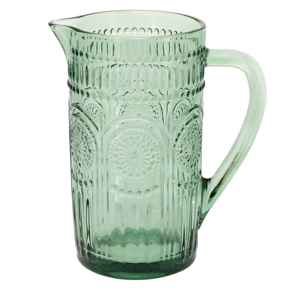 Green glass pitcher with decorative patterns on a white background