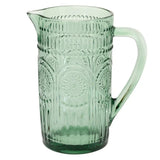 Green glass pitcher with decorative patterns on a white background
