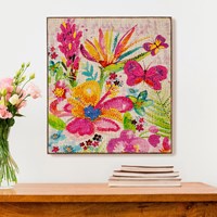 A canvas wall decor featuring a colorful floral and butterfly pattern, displayed above a table.