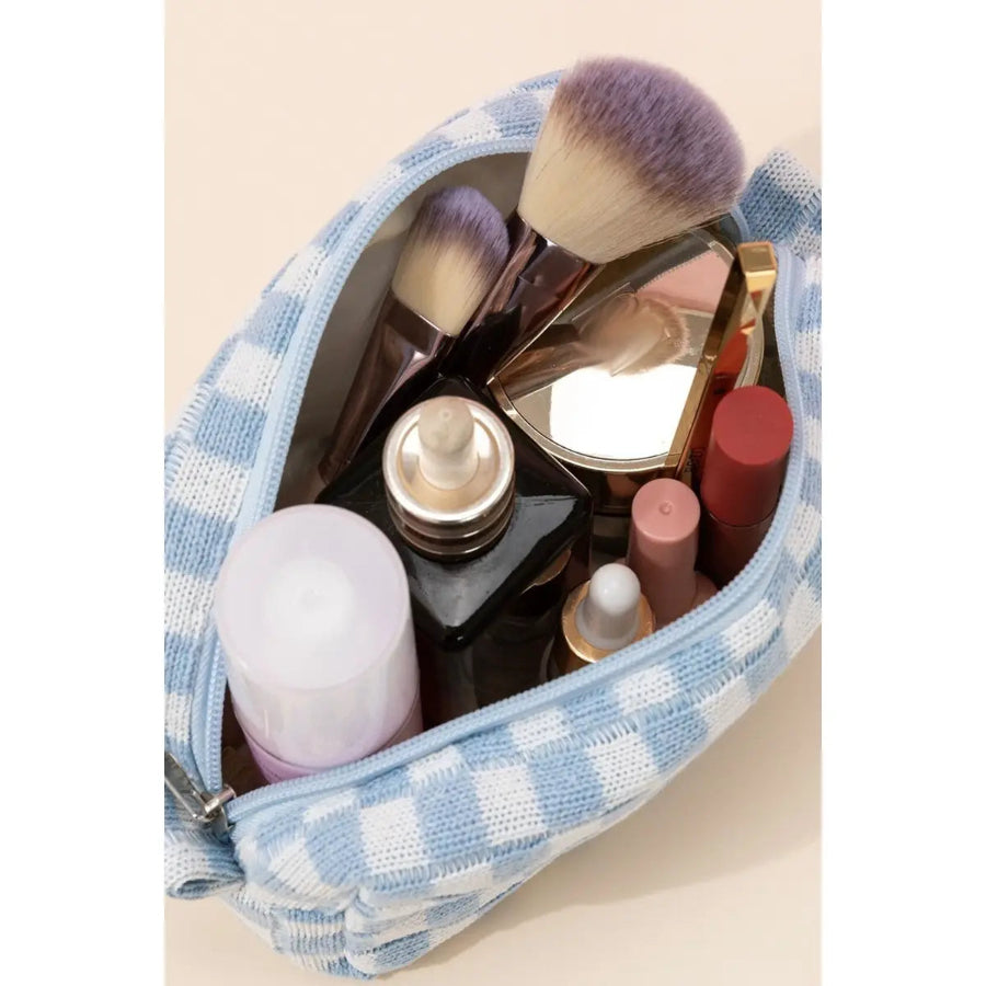 Makeup bag with various cosmetic items including bottles, brushes, and mirrors on a beige background