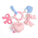 Pink and blue baby teething ring with bow designs on a white background