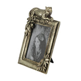An ornate antique bronze picture frame featuring a leopard figurine on top and leafy corner details, holding a black-and-white portrait of a woman. The frame is shown standing on a small black support against a plain white background.