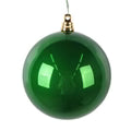 Green glass ornament on a gold stand against a white background