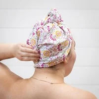 A person is shown from the back with a multicolored floral head wrap tied around their head.