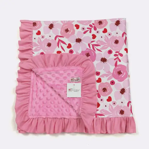 Pink floral baby blanket with ruffled edge on a white background