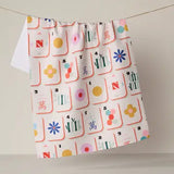 A white curtain panel with a colorful Mahjong tile pattern, hanging from a thin cord against a plain light beige wall.