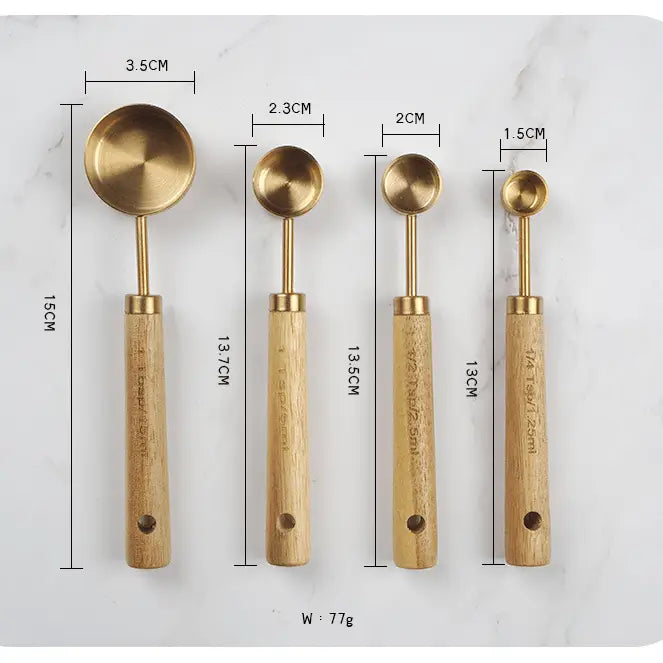 Set of four brass measuring spoons with wooden handles, shown with measurements on a white background.