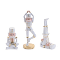 Three ceramic nutcrackers in yoga poses on a white background