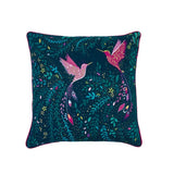 A square decorative throw pillow featuring a vibrant, detailed print of two hummingbirds amidst lush tropical foliage. The background of the print is a deep teal, while the birds and floral elements are highlighted in bright pink, purple, and yellow.