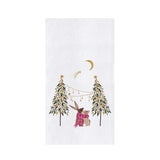 A white rectangular textile item, likely a tea towel or napkin, featuring a festive embroidered design of a rabbit in a pink scarf under two decorated Christmas trees, a crescent moon, and a shooting star.