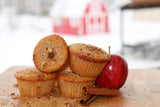 Apple muffins with a red apple and cinnamon stick on a wooden surface