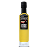 A tall glass bottle of Olivelle Brown Butter infused olive oil, featuring a black cap and a black label with white text and a small red spoon graphic, set against a plain white background.