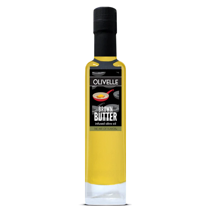 A tall glass bottle of Olivelle Brown Butter infused olive oil, featuring a black cap and a black label with white text and a small red spoon graphic, set against a plain white background.
