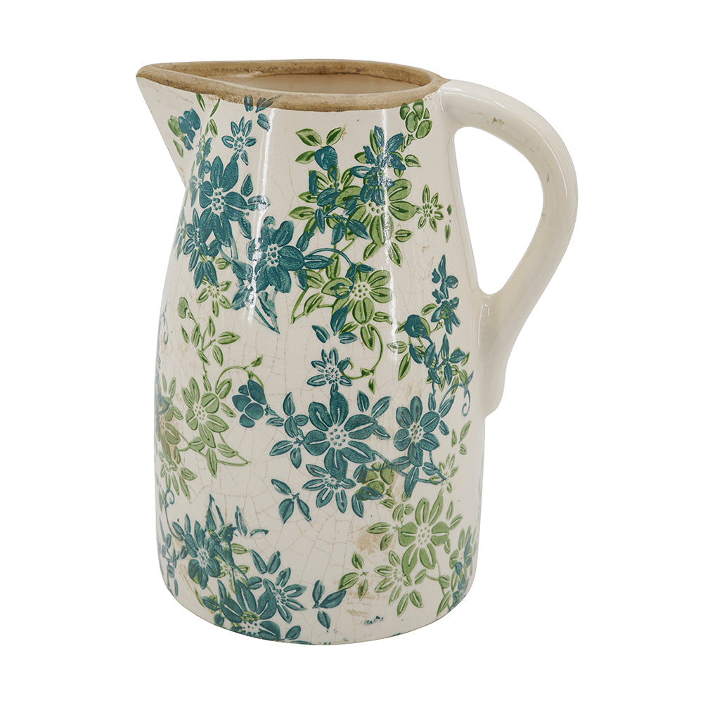 A ceramic pitcher with a cream-colored body, decorated with a blue and green floral pattern, and featuring a natural unglazed brown rim.
