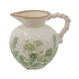 A vintage ceramic pitcher with a rounded body, twisted handle, and wide pouring spout, decorated with green botanical patterns on a cream-colored glaze.
