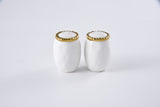 Two white ceramic salt and pepper shakers with gold rims on a light gray background