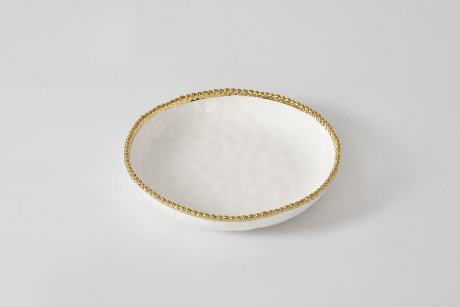 White ceramic bowl with gold rim on a light gray background