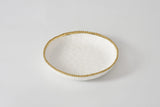 White ceramic bowl with gold rim on a light gray background