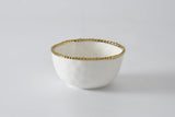 White bowl with gold rim on a light gray background