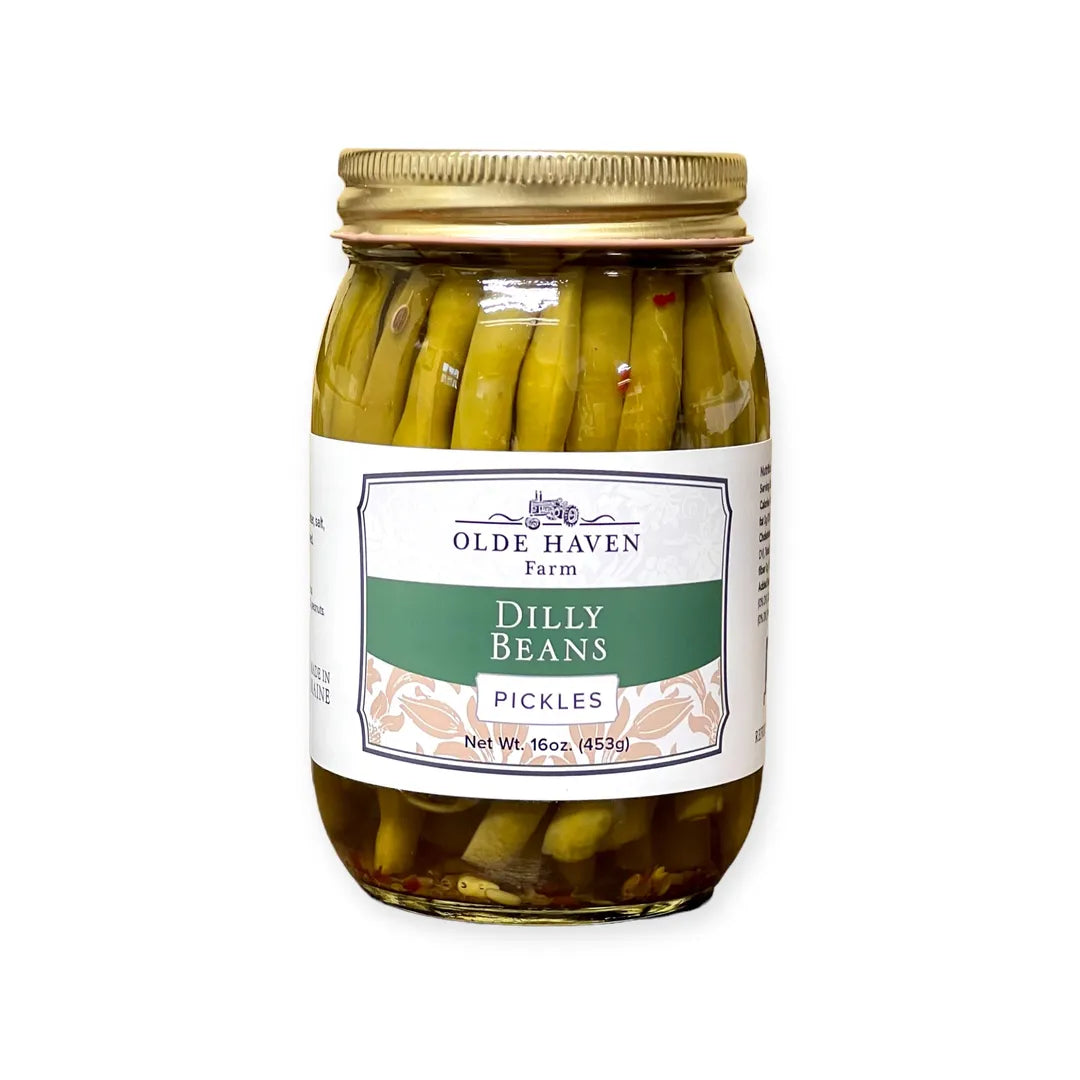 A jar of Olde Haven Farm Dilly Beans Pickles with a white and green label and a gold metal lid, set against a plain white background.