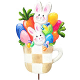 Decorative Easter scene with bunnies, carrots, and eggs in a teacup on a white background