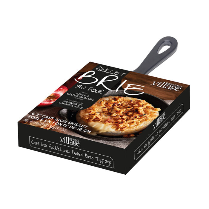 Box of a cast iron skillet with a baked brie on top, featuring the brand 'Village'.