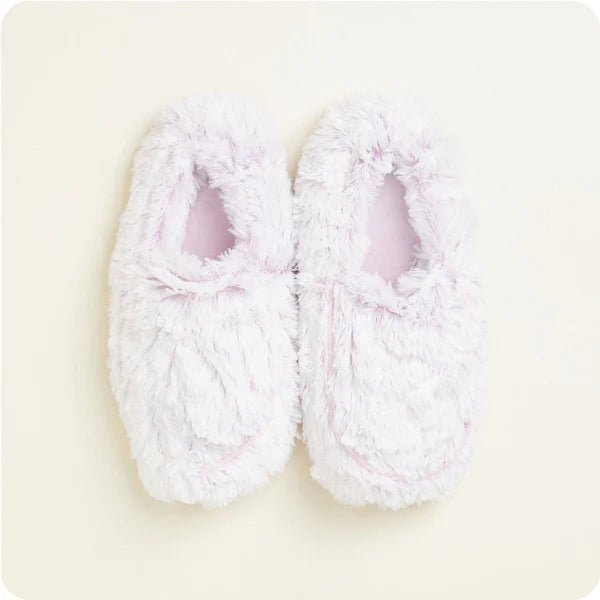 Pair of white fluffy slippers on a light beige background