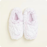 Pair of white fluffy slippers on a light beige background