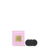 Pink packaging with gold label and two black coasters on a white background