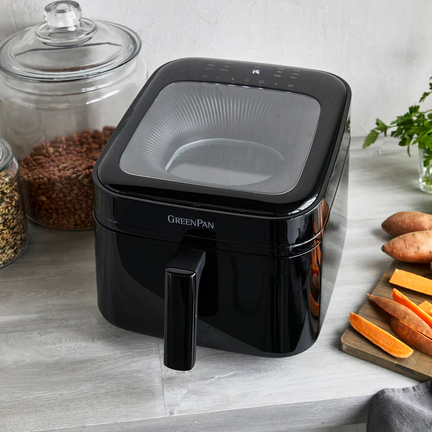 Black GreenPan air fryer on a kitchen counter with ingredients in the background