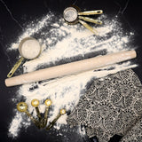 Rolling pin and measuring cups on a black surface with flour