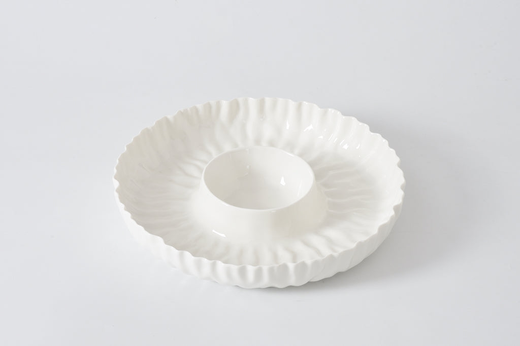 White ceramic dish with decorative rim on a light gray background