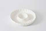 White ceramic dish with decorative rim on a light gray background