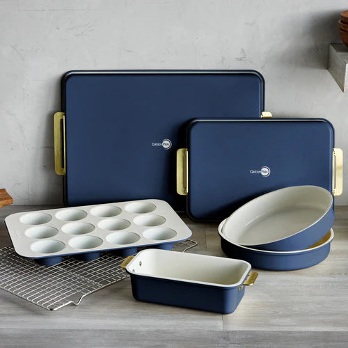 Set of blue ceramic baking dishes with gold handles on a wooden surface.