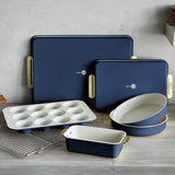 Set of blue ceramic baking dishes with gold handles on a wooden surface.