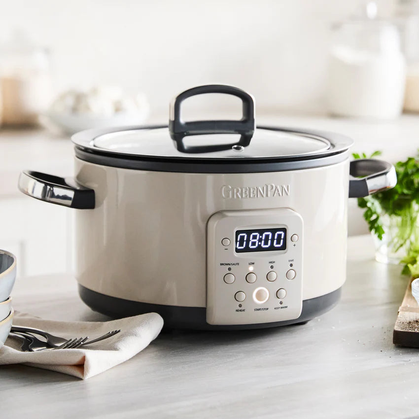 White slow cooker with digital display on a kitchen counter, featuring the brand 'GreenPan'.