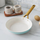 White frying pan with gold handle on a marble countertop