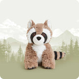 A plush raccoon toy centered against a soft, stylized forest and mountain backdrop. The raccoon has brown and white fur with black facial markings and a black-and-brown striped tail.