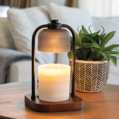 Candle in a holder on a wooden table with a plant in the background
