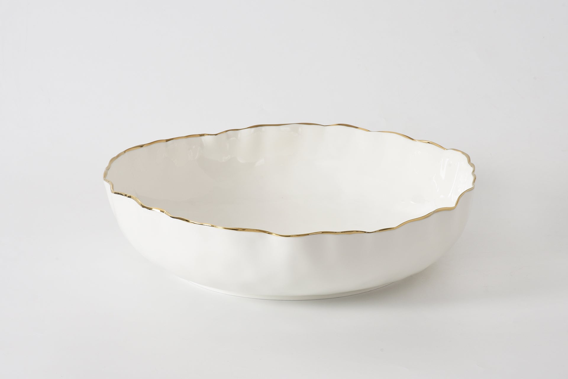 White ceramic bowl with gold rim on a white background