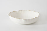 White ceramic bowl with gold rim on a white background