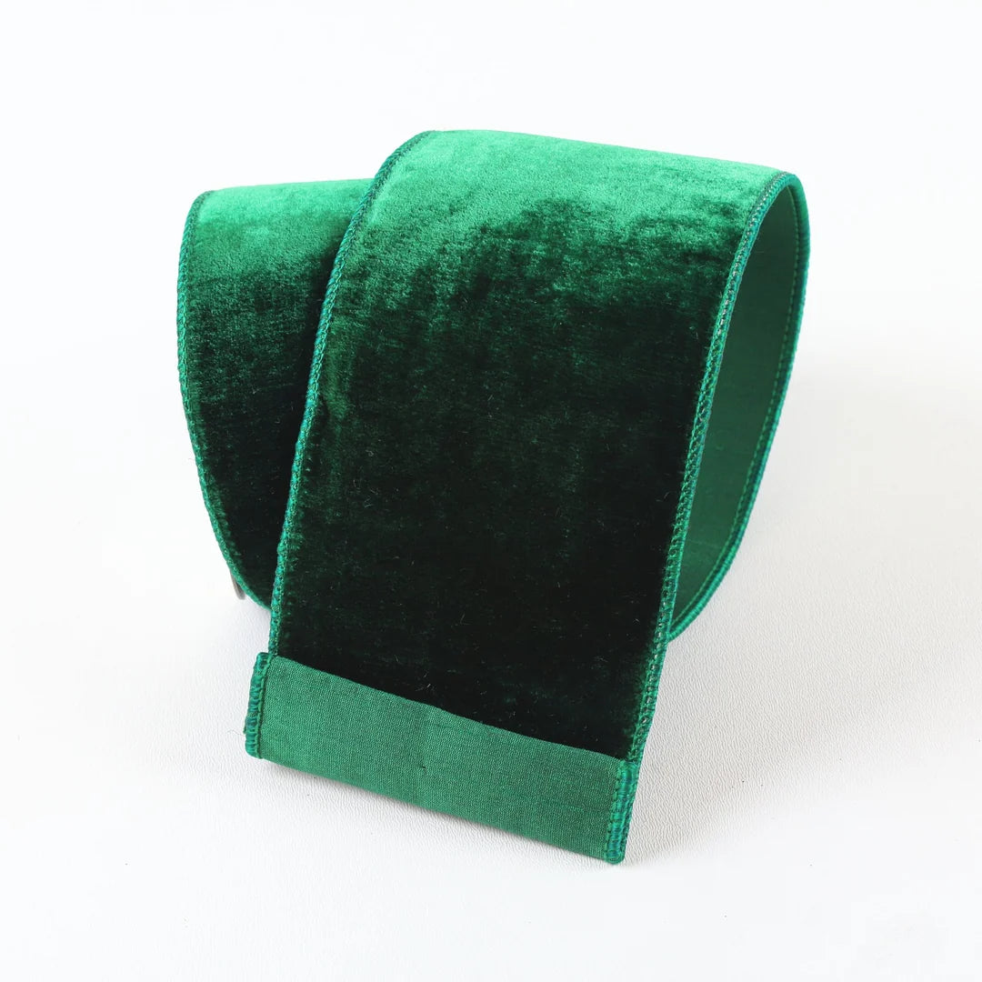 A roll of emerald green velvet ribbon or trim, shown on a clean white background.